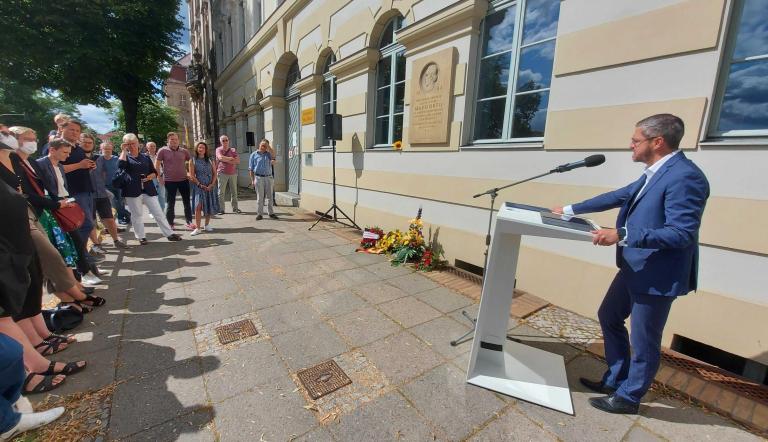 Oberbürgermeister Mike Schubert steht vor dem Geburtshaus von Max Dortu in der Dortustraße und spricht zu Gästen der Gedenkveranstaltung.