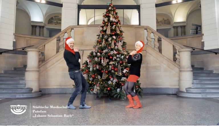 Ein Sänger und eine Sängerin posieren im Weihnachtslook vor einem Weihnachtsbaum