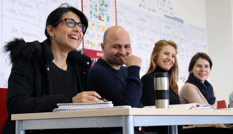 Das Foto zeigt vier an einem Tisch sitzende Personen mit Arbeitsunterlagen.