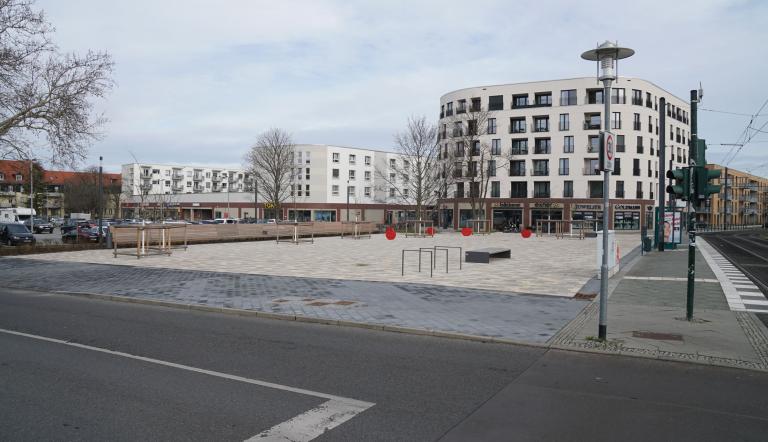 Johan-Bouman-Platz Das Bild zeigt ie Fläche des Johan-Bouman-Platzes, links eine Reihe von Sitzbänken,im Hintergrund Häuser mit Ladengeschäften.