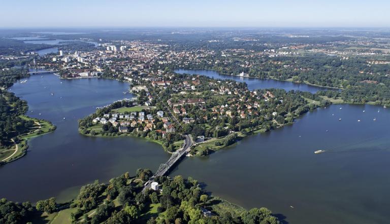 Die Luftaufnahme zeigt Potsdam inmitten von Seen und Flüssen. Im Vordergrund ist die bekannte Glienicker Brücke zu sehen.