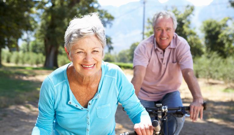 Radfahrende Senioren Das Foto zeigt im Vordergrund eine Seniorin und dahinter einen Senior auf dem Fahrrad.