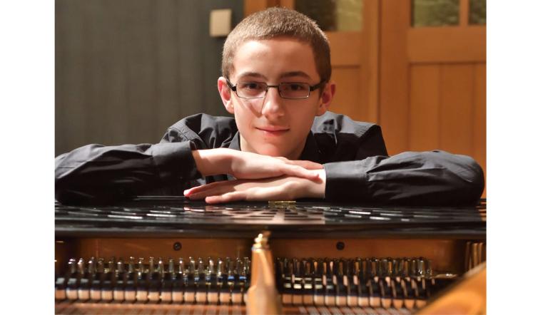 Ein junger Pianist schaut über die Saiten seines Konzertflügels