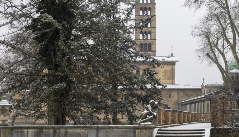 Verschneite Parktreppen mit Bäumen; im Hintergrund ein historischer Kirchturm und Gebäudefassaden., Foto: André Stiebitz, Lizenz: PMSG