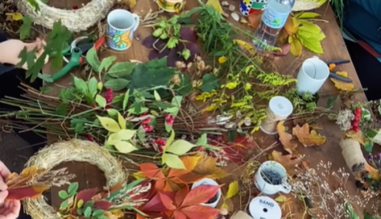 Draufsicht auf einen Tisch, an dem Hände aus bunten Herbstblättern, Beeren und Zweigen Kränze binden., Foto: Nicole Riekeles , Lizenz: Nicole Riekeles 