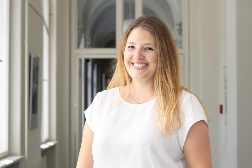 Sie sehen die Beauftragte für Migration und Integration Dr. Amanda Palenberg, welche in einem Lichtdurchfluteten Flur steht