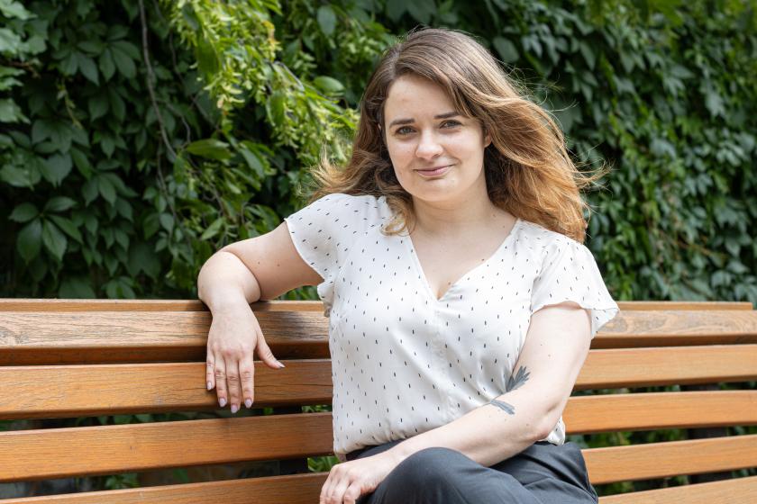 Die Gleichstellungsbeauftragte und Leiterin des Büros für Chancengleichheit und Vielfalt Claudia Sprengel sitzt auf einer braunen Brank, im Hintergrund ist eine grüne Hecke