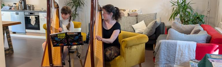 Eine Frau und ein Mädchen spielen gemeinsam Harfe.