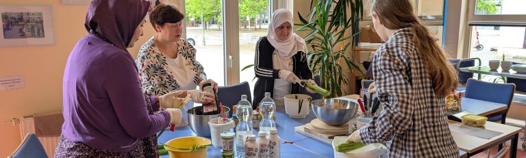 Vier Frauen bereiten an einem Tisch ein Gericht zu.
