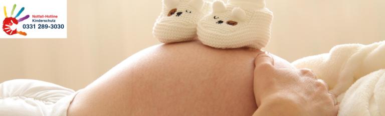 Eine werdende Mutter zeigt ihren Schwangerschaftsbauch. Eine werdende Mutter zeigt ihren Schwangerschaftsbauch, die Notfall-Hotline Kinderschutz von Potsdam ist zu sehen: 0331 289 3030