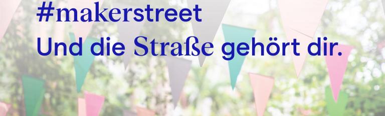 Schrift über Wimpeln, die in den Bäumen gespannt sind.