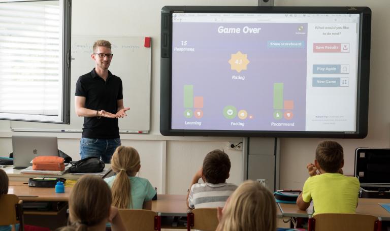 Lehrer und Schüler vor digitaler Tafel